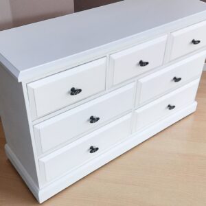 a white dresser with black handles