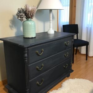 a dresser with a lamp and a vase on top