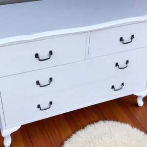 a white dresser with black handles