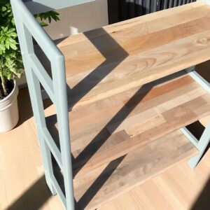 a wood shelf with a plant in the background
